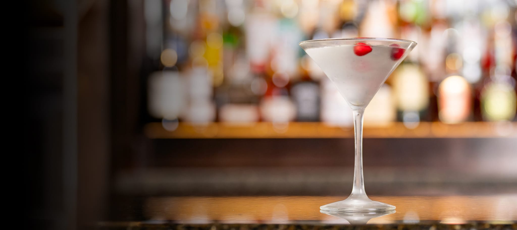 Cosmopolitan cocktail with frozen cramberries, sitting on a bartop